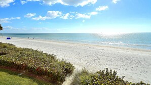 A beach with a clear sky and calm sea. - Tides 1-211 (North Redington Beach)