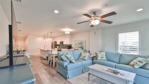 A modern living room with a blue sofa, a coffee table, and a ceiling fan. - Madeira Del Mar 301 (Madeira Beach)
