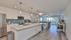A modern kitchen with white cabinetry, stainless steel appliances, and pendant lighting. - Madeira Del Mar 301 (Madeira Beach)