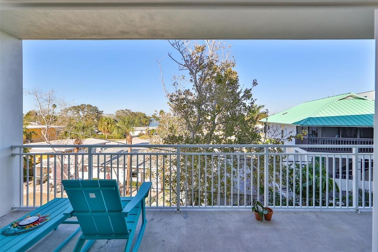 A balcony with a view of a tree and buildings.