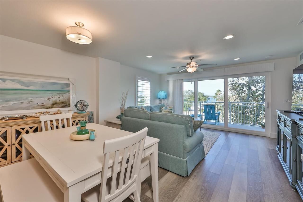 A spacious living area with a dining table, a sofa, and a balcony with a view.