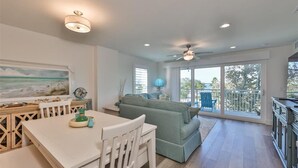 A spacious living area with a dining table, a sofa, and a balcony with a view. - Madeira Del Mar 301 (Madeira Beach)