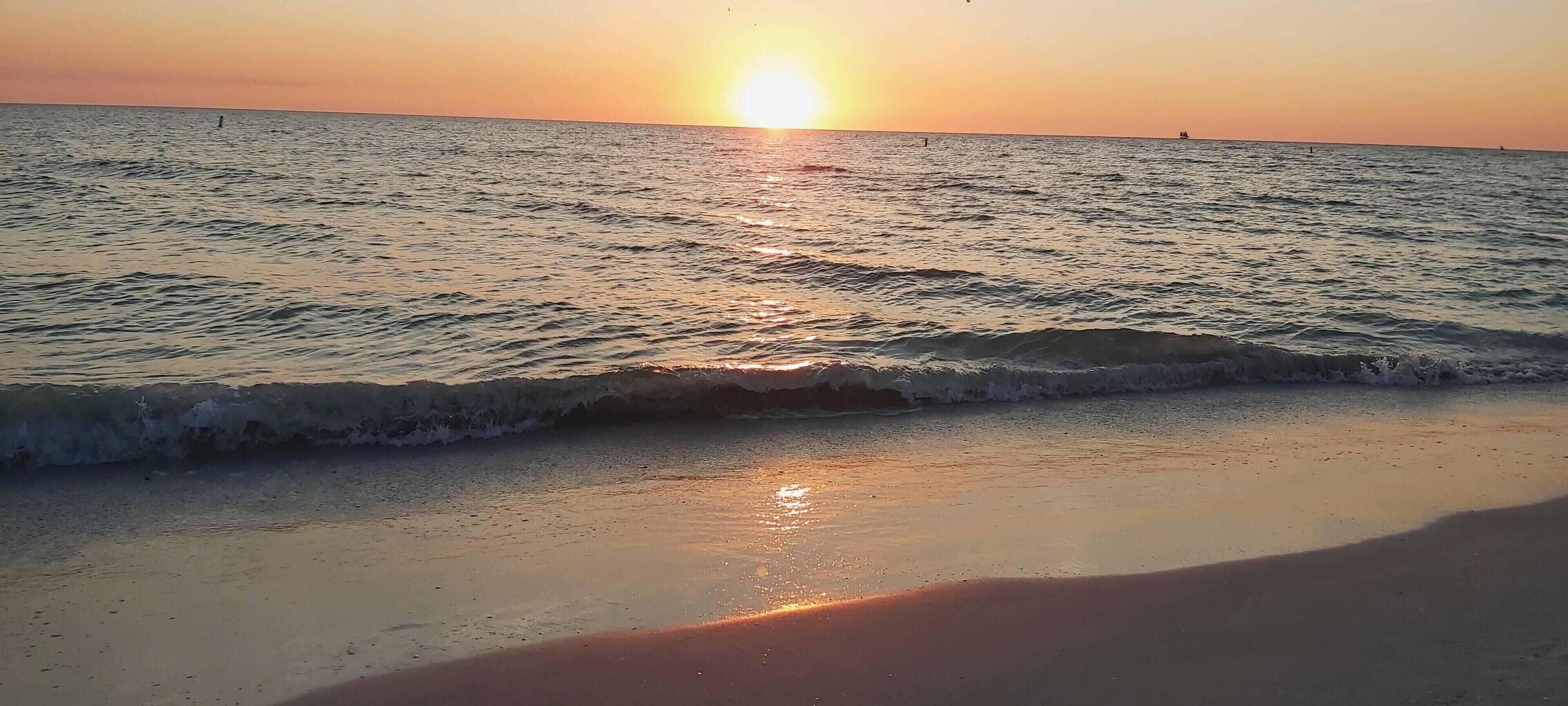 A beach with waves at sunset.