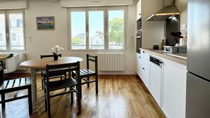 Une cuisine moderne avec un coin repas, de grandes fenêtres et une vue sur l’extérieur.