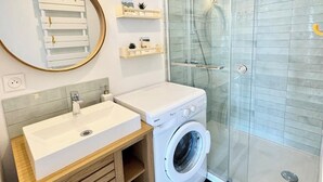 Une salle de bain moderne avec une douche en verre, un lavabo et un lave-linge.