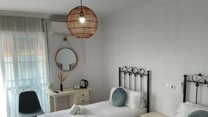 Une chambre d’hôtel avec deux lits, un bureau, une chaise, un miroir et un luminaire suspendu.