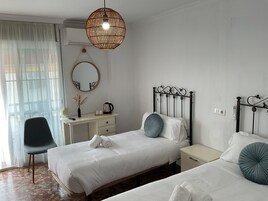Une chambre d’hôtel avec deux lits, un bureau, une chaise, un miroir et un luminaire suspendu.