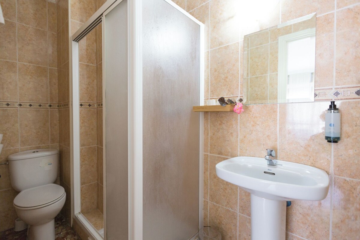 A bathroom with a shower, toilet, and sink.