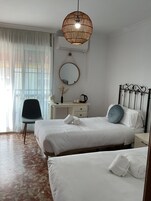 Une chambre d’hôtel avec deux lits, un bureau, une chaise, un luminaire suspendu et un miroir.