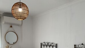 Une chambre d’hôtel avec deux lits simples, une table de chevet avec une bouilloire, un miroir et un luminaire suspendu.