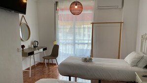 Une chambre d’hôtel avec deux lits, un bureau, une chaise et une grande fenêtre donnant sur un beau paysage.