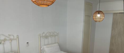 Two single beds with white linens and towels, a bedside table with a remote control, and a wall-mounted phone.