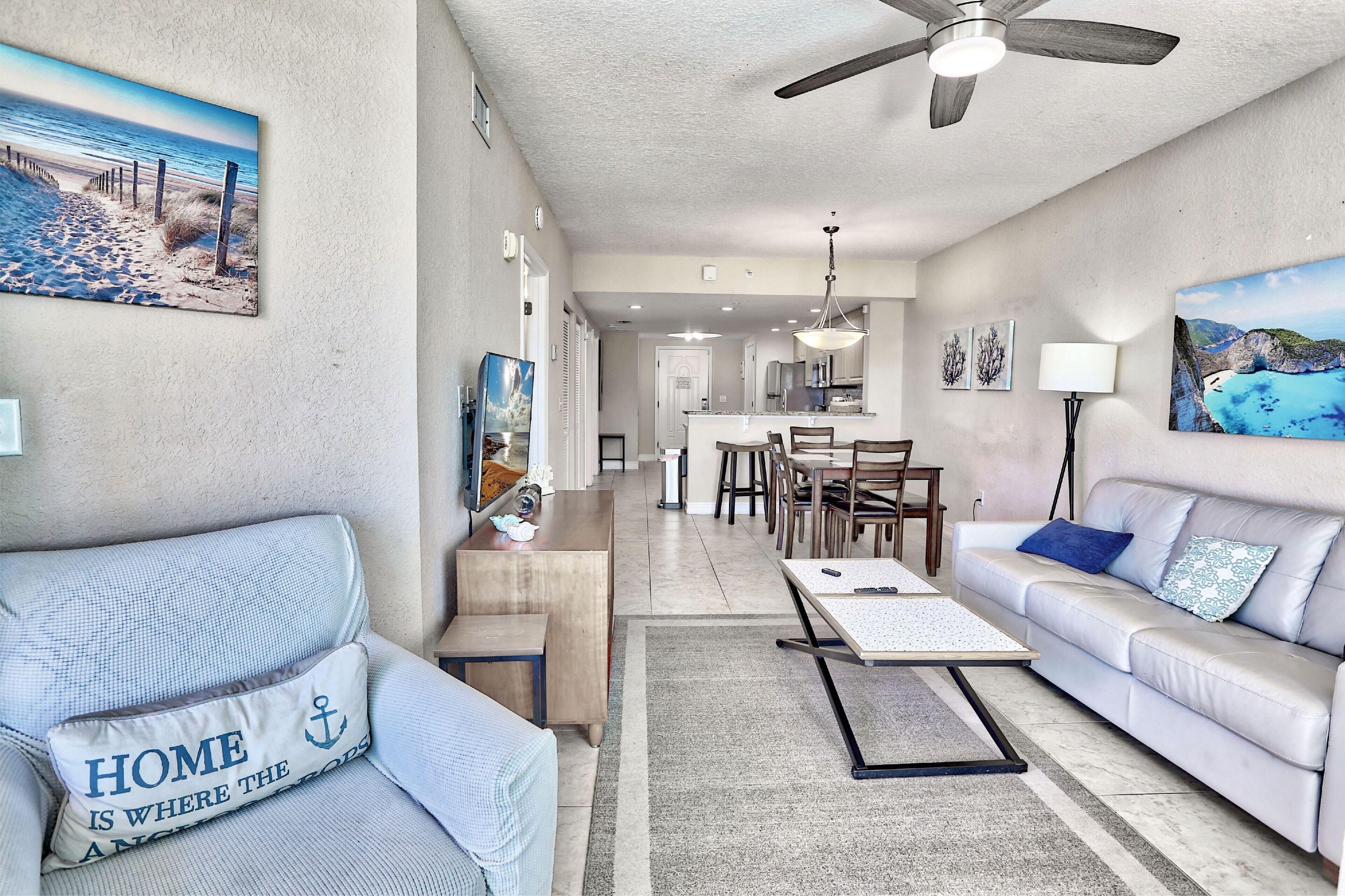 A living room with a sofa, coffee table, and a dining area with chairs and a table.