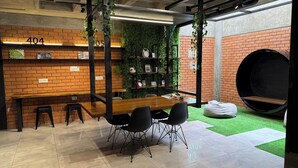 A modern indoor space with a brick wall, a wooden table with chairs, a hanging plant, and a unique circular seating area. - A must-see studio apartment in Sirari-Equipetrol (Santa Cruz de la Sierra)