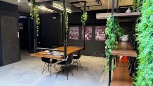 A modern office space with a wooden table, black chairs, and hanging plants. - A must-see studio apartment in Sirari-Equipetrol (Santa Cruz de la Sierra)
