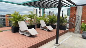 A rooftop terrace with two lounge chairs, potted plants, and a view of the city skyline. - A must-see studio apartment in Sirari-Equipetrol (Santa Cruz de la Sierra)