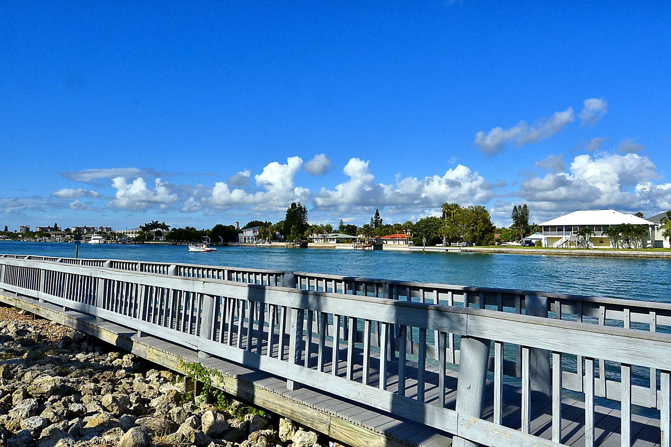 Een houten steiger die zich uitstrekt over een wateroppervlak, met een heldere lucht en verspreide wolken.