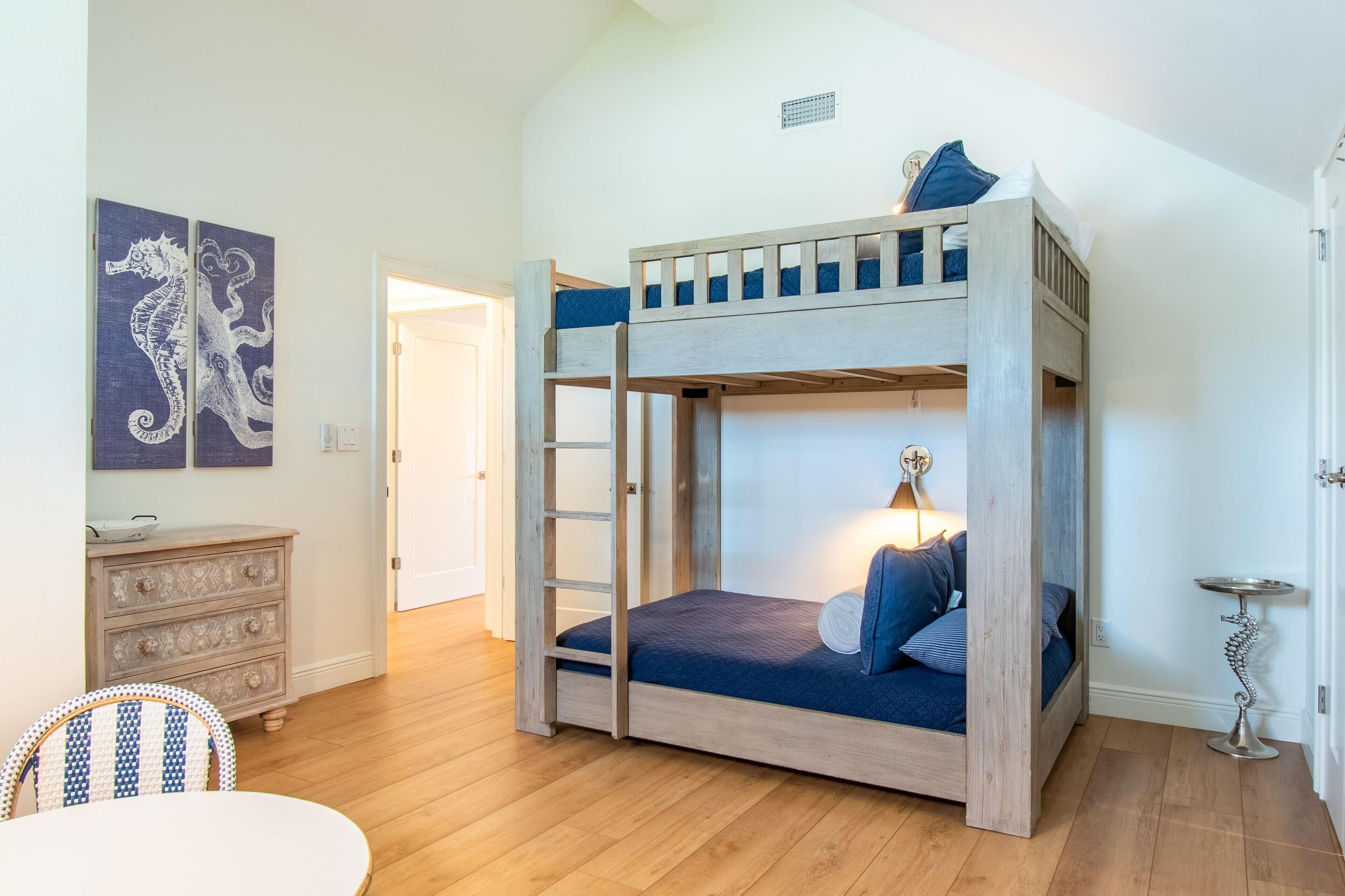 Habitación con literas, una escalera, un aparador y un cuadro de un caballito de mar.