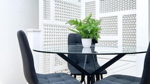 A modern dining area with a glass table and black chairs, a potted plant, and a white lattice partition. - Museum ST Central Soho Apartment (Greater London)