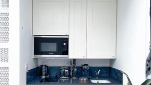 A compact kitchen with white cabinets, a microwave, a coffee maker, and a sink. - Museum ST Central Soho Apartment (Greater London)
