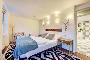 A bedroom with a bed, bedside tables, a wall-mounted light fixture, and a patterned rug. - Prime Location Marylebone 4 Bed Designer Flat (Greater London)