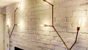A wall-mounted light fixture with exposed bulbs against a white brick wall. - Prime Location Marylebone 4 Bed Designer Flat (Greater London)