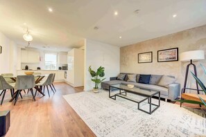 A modern living room with a sofa, coffee table, and dining area with chairs.