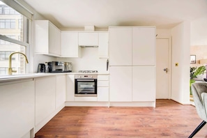 A modern kitchen with white cabinets, a built-in oven, and a window with a view of buildings.