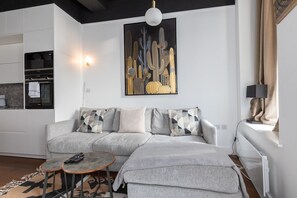 A modern living room with a grey sofa, a small round table, and a large abstract painting on the wall.