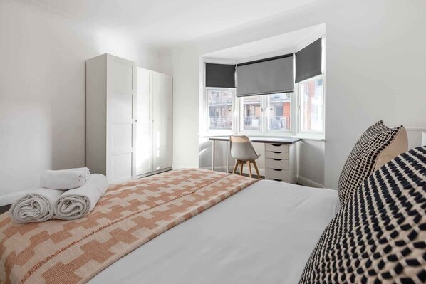 Een hotelkamer met een bed, een bureau, een stoel en een kledingkast.