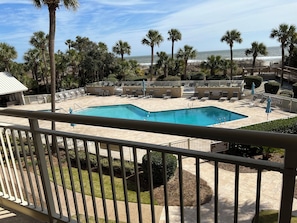 Relax by the resort pool, surrounded by palm trees and a clear ocean view.