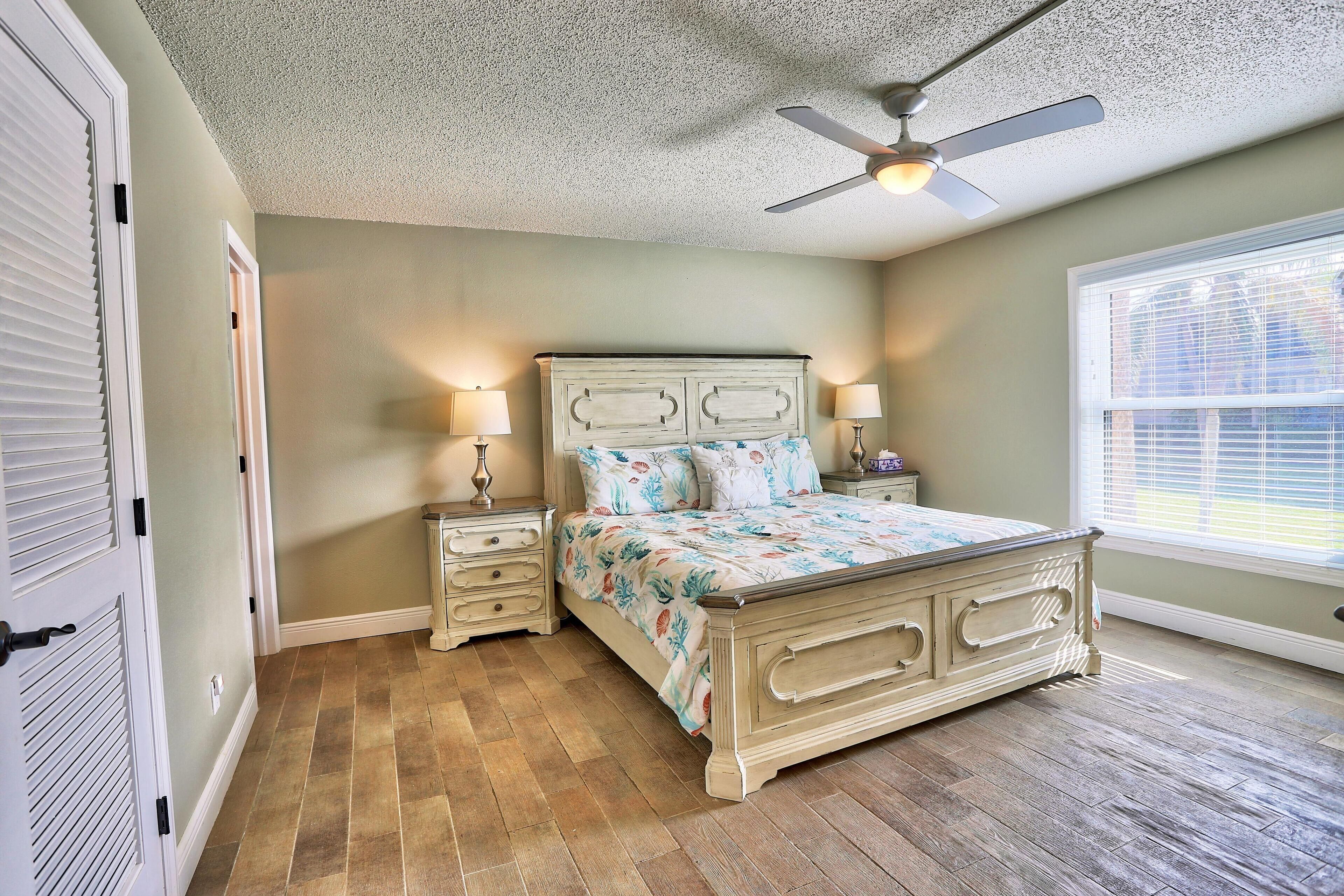 A bedroom with a bed, bedside tables, a ceiling fan, and a window.