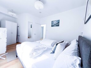 Une chambre moderne avec un grand lit, une armoire, un miroir et un ventilateur de plafond.
