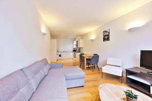 A modern living room with a grey sectional sofa, a TV, and a dining area with a table and chairs. - Lovely 2 BED Tower Bridge Apartment Sleeps 6 (London)