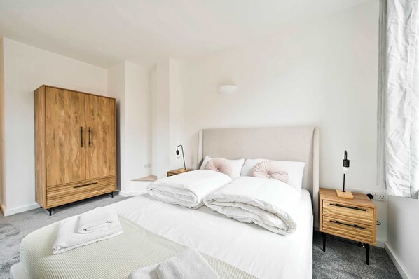 A bedroom with a bed, a wooden wardrobe, a bedside table with a lamp, and a nightstand. - Lovely 2 BED Tower Bridge Apartment Sleeps 6 (London)