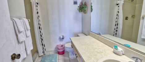 A bathroom with a beige sink, a mirror, a toilet, and a shower area.