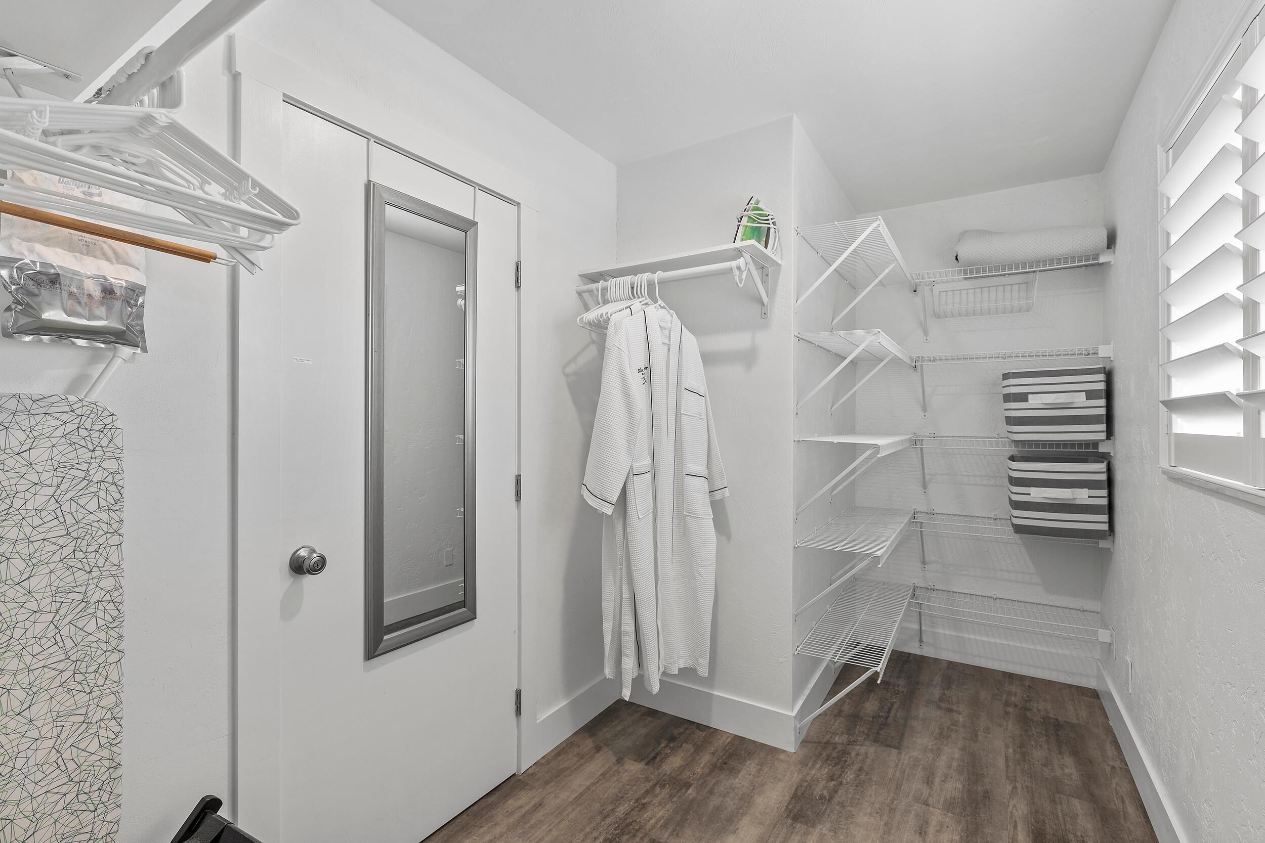 A walk-in closet with open shelving, a hanging rod, and a door with a mirror.
