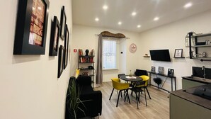 A modern living room with a dining area, a bookshelf, a flat-screen TV, and a window with curtains. - Stylish&Renovated Apt in Trastevere ac/wi-fi (Roma)