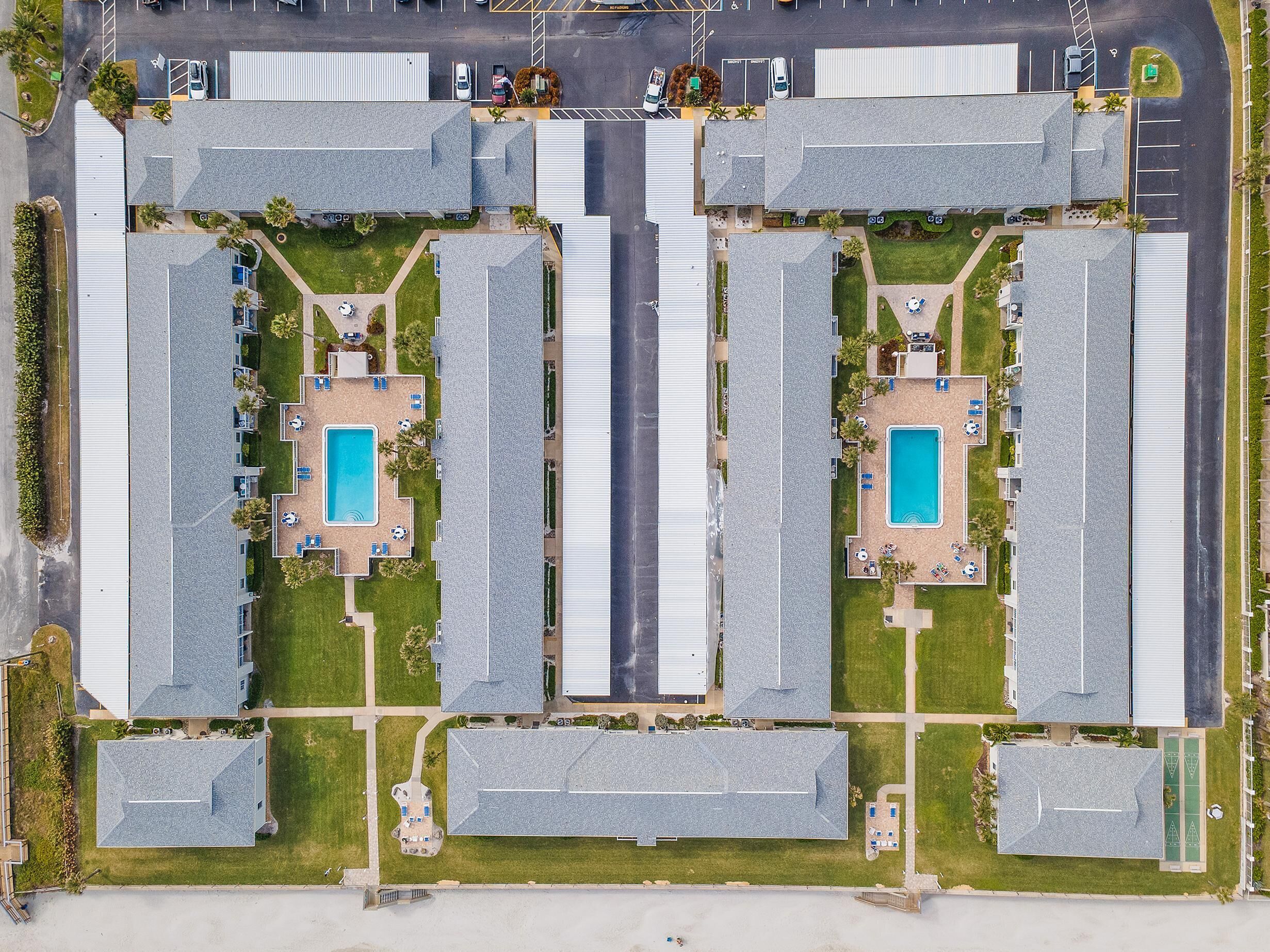 Vista aérea de un hotel con varias edificaciones, cada una con piscina y zonas de estar al aire libre.