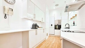 A modern kitchen with white cabinets, a built-in oven, and a coffee machine. - Wonderful Fitzrovia 3 Bed Apartment (Greater London)