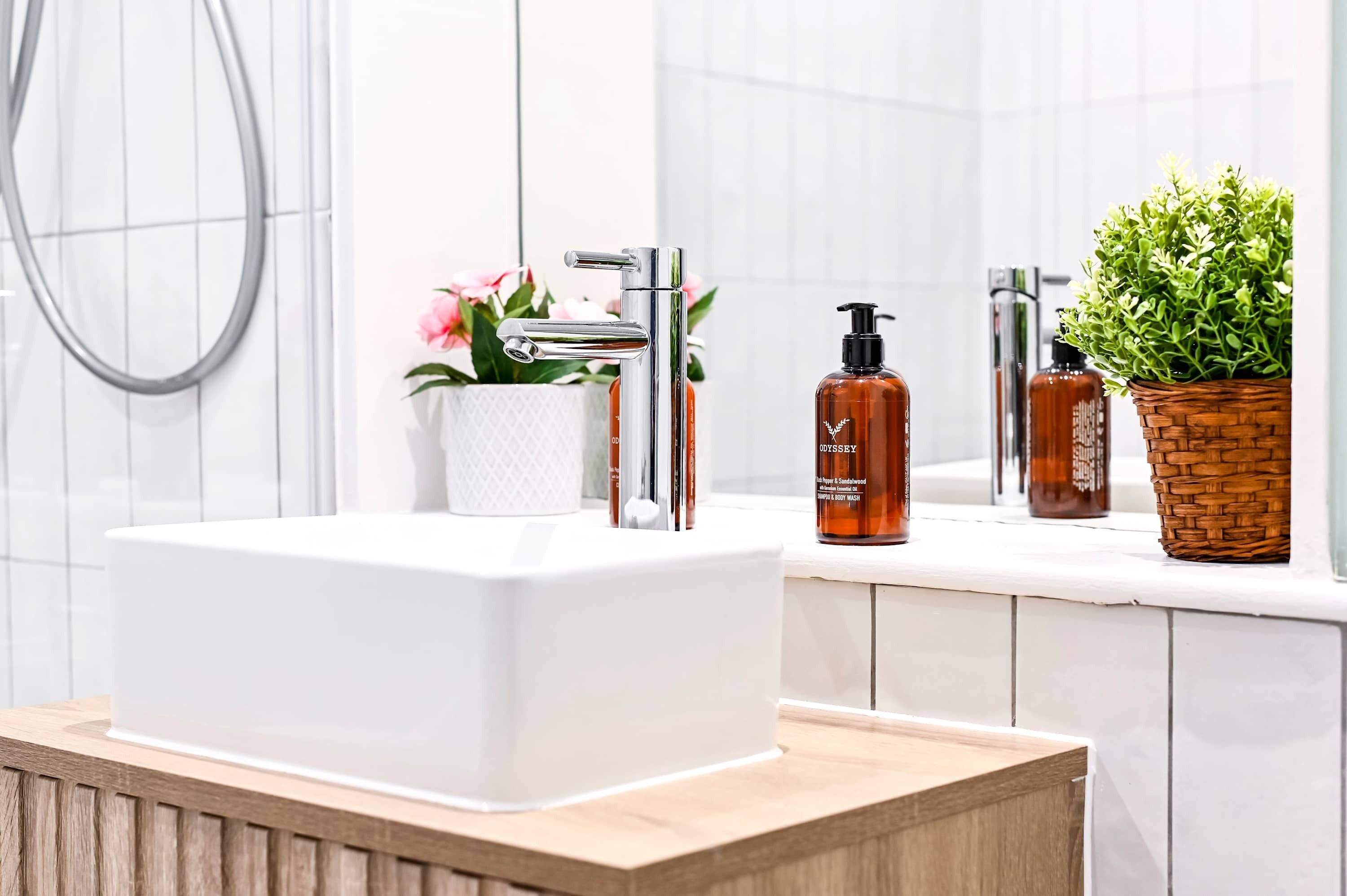 Une salle de bain moderne avec un lavabo blanc, un robinet chromé et une plante en pot.