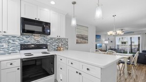 Una cocina moderna con armarios blancos, un microondas negro y un rebozado de azulejos.