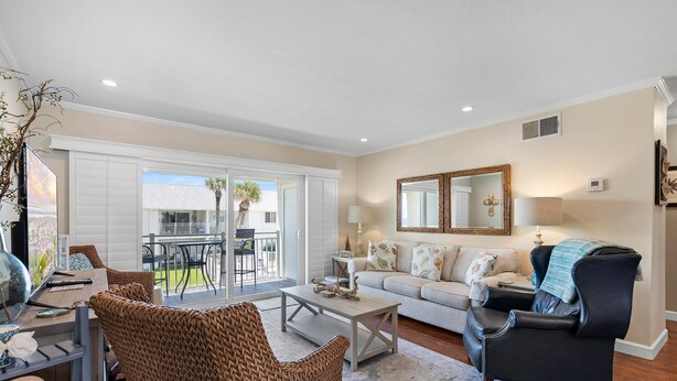A living room with a sofa, armchairs, a coffee table, and a dining area with chairs and a table.
