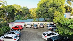 A parking lot with multiple cars parked in a gravel area, surrounded by greenery and trees. - Villa Junior # 1 w/ Pool & Kitchen – Minutes from Manuel Antonio Beach (Quepos)