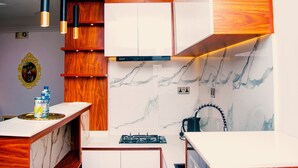 A modern kitchen with white cabinets, a marble backsplash, and wooden accents. - Ai-Royal Hotel & Suites (Ikorodu)