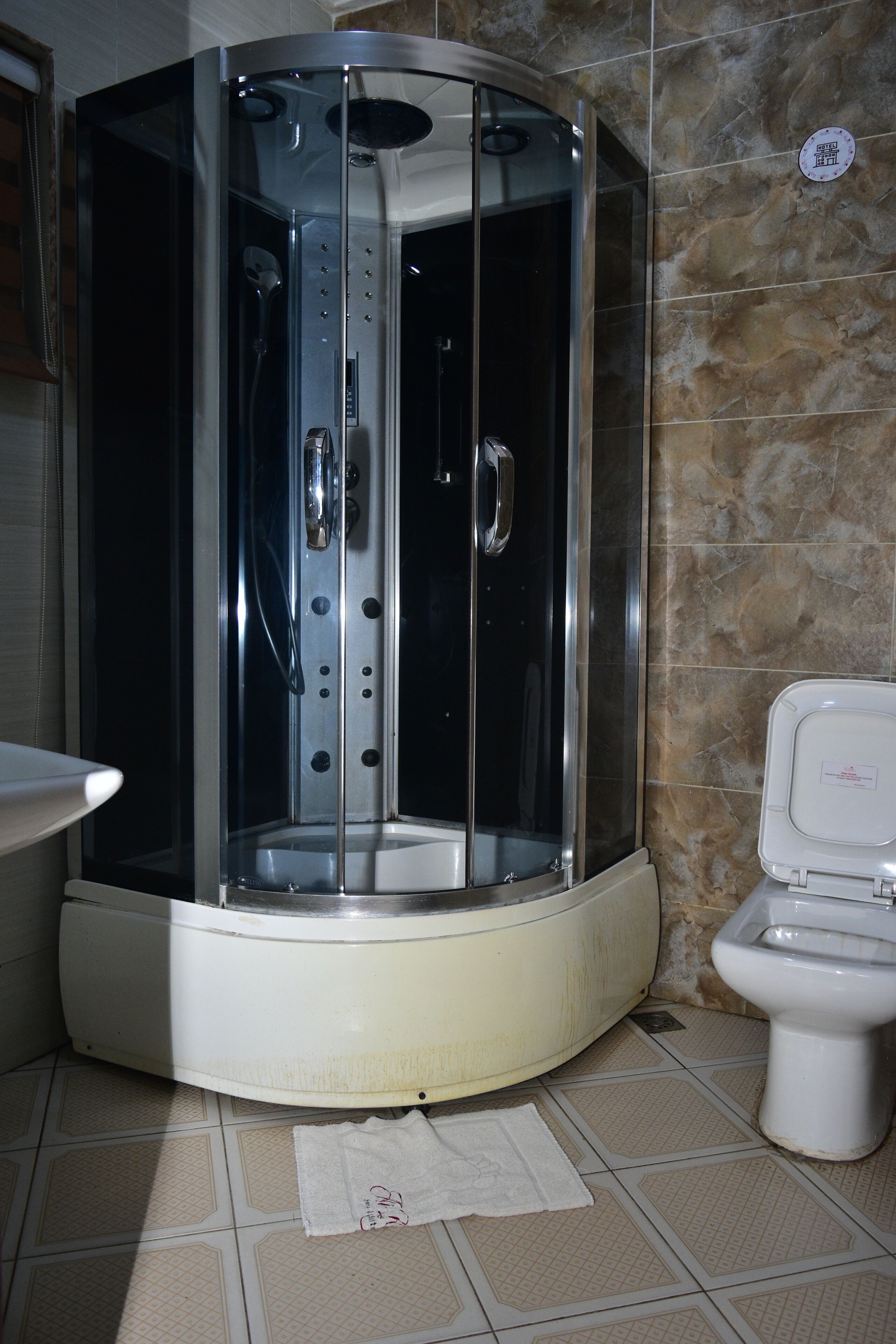 A corner shower enclosure with a glass door, a toilet, and a towel on the floor.