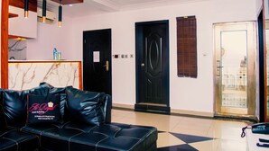 A hotel lobby with a black leather sofa, a reception desk, and a black door. - Ai-Royal Hotel & Suites (Ikorodu)