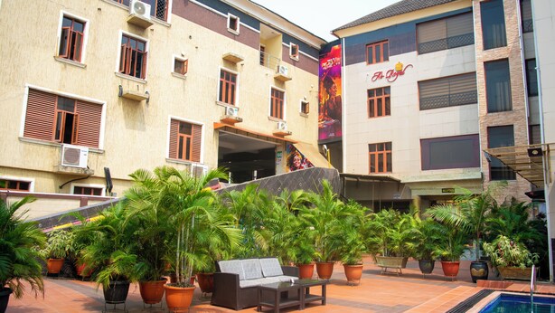 A hotel courtyard with a pool, outdoor seating, and potted plants. - Ai-Royal Hotel & Suites (Ikorodu)