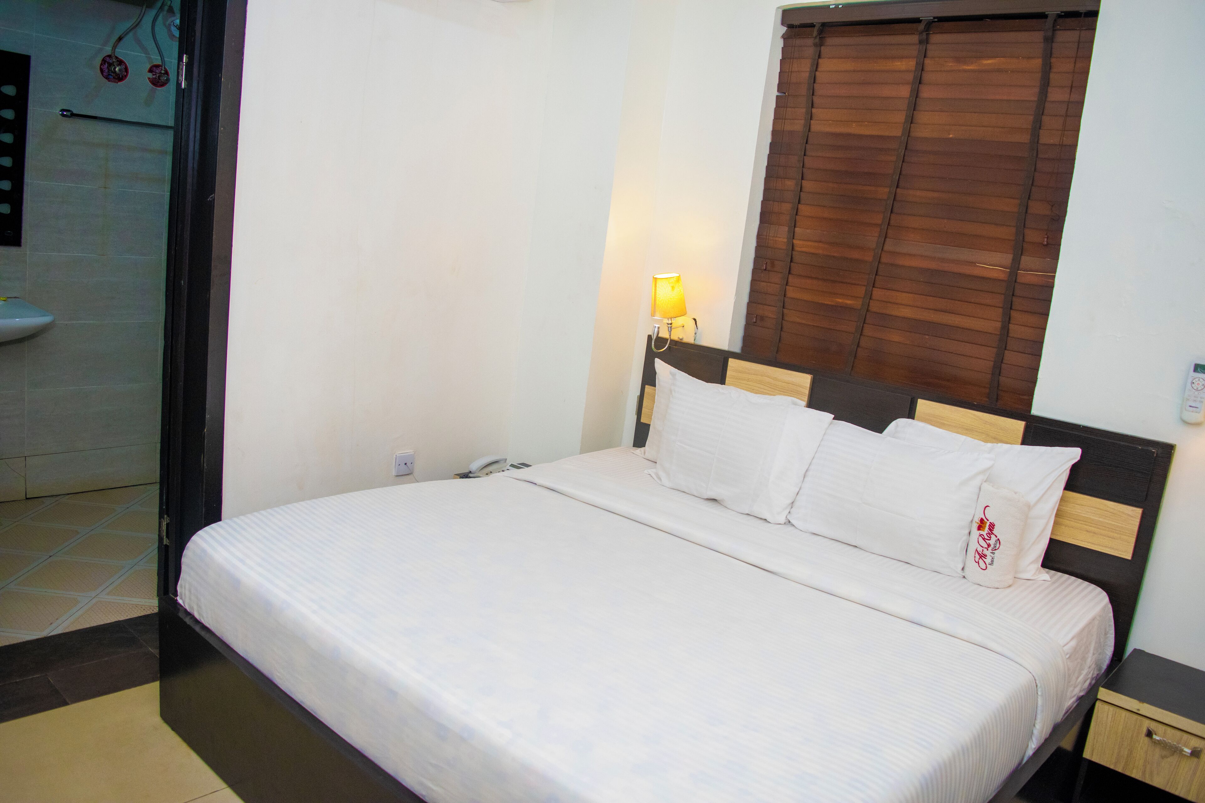 A neatly made bed with white linens in a hotel room.