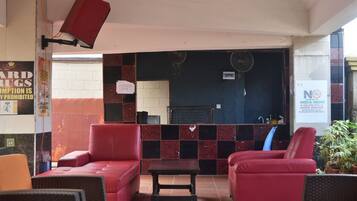 A hotel lobby with red sofas, a small table, and a tiled wall.